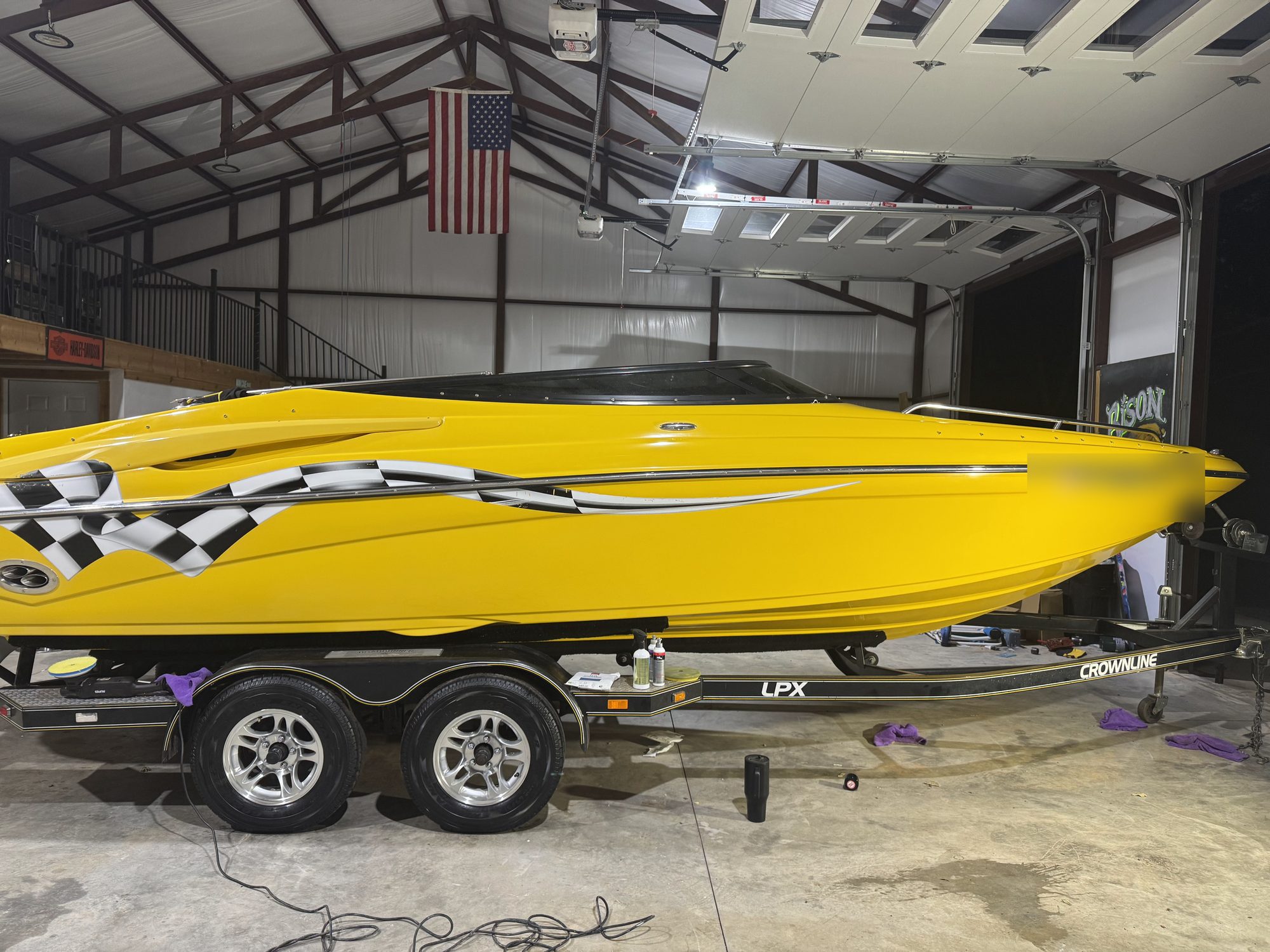 Yellow Crownline LPX on its trailer in the shop, hull polished to a mirror finish