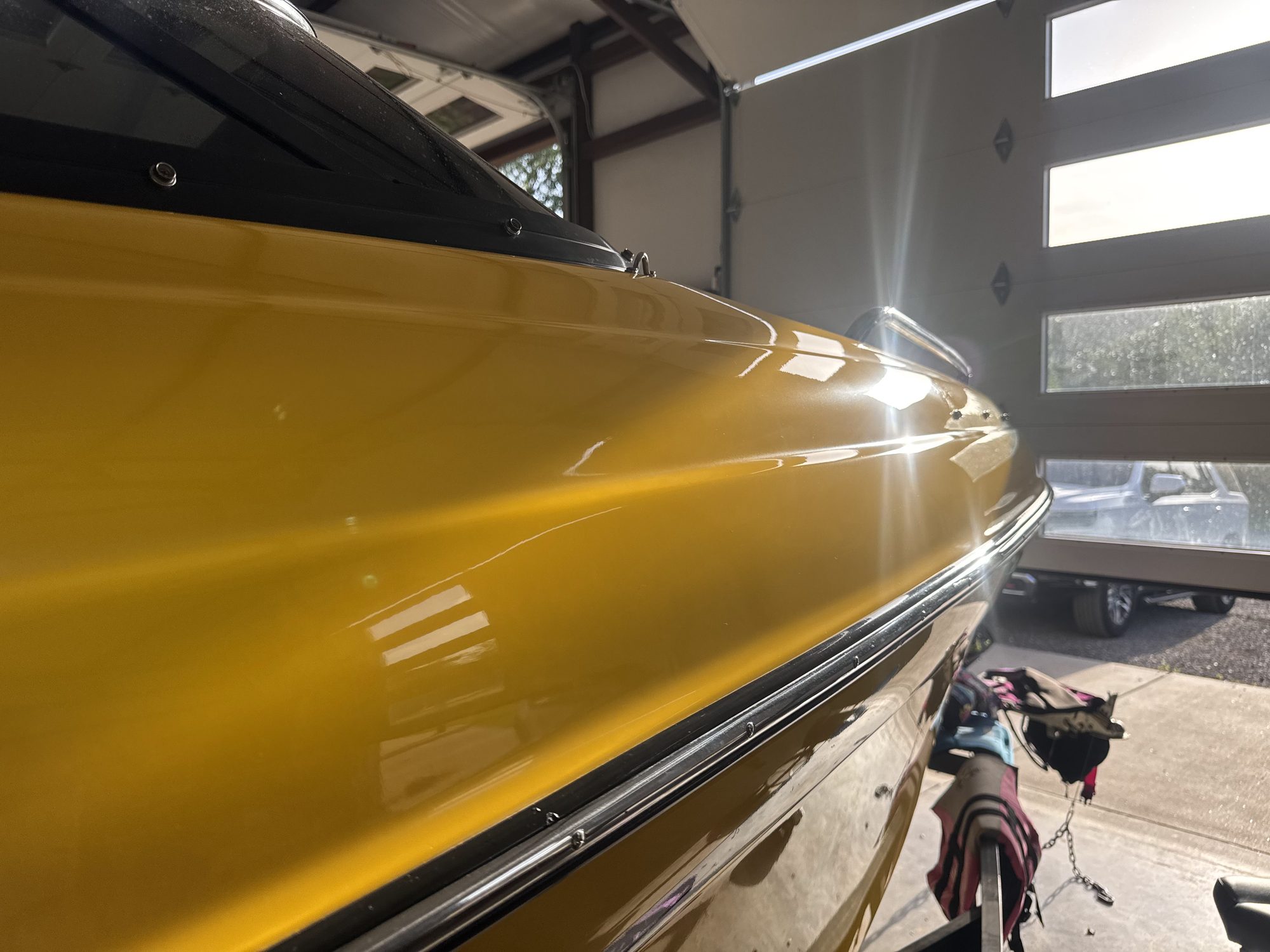 Close-up of the polished yellow gelcoat reflecting the shop lights like a mirror